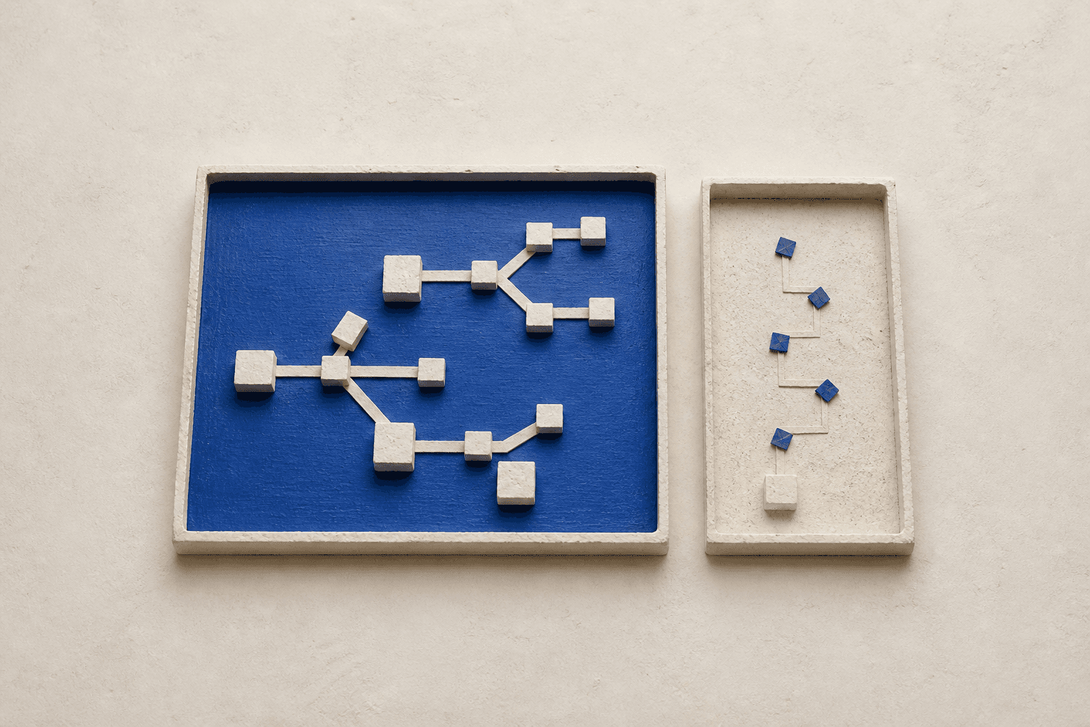 Top-down view of a generated still life with two ivory plaster-framed rectangular fields, the larger containing a network of blocks on a cobalt surface.