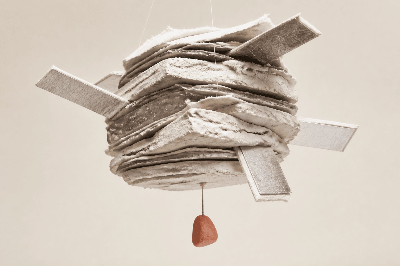 Generated editorial illustration of a suspended bundle of paper, plaster, resin and aluminium, extended by four tabs and weighted by a small coral stone.